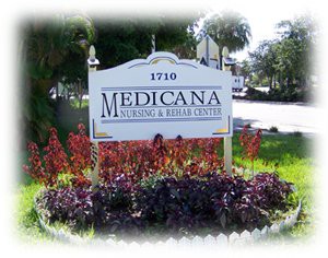Sign for Medicana Nursing and Rehab Center surrounded by plants.