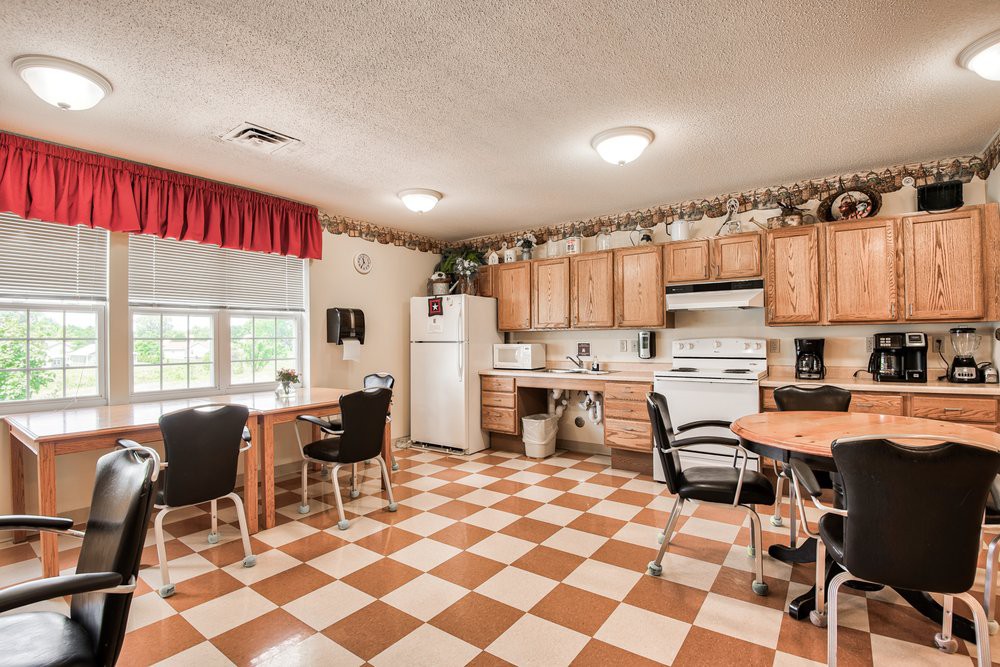 A spacious kitchen with checkered flooring, wooden cabinets, and modern appliances.