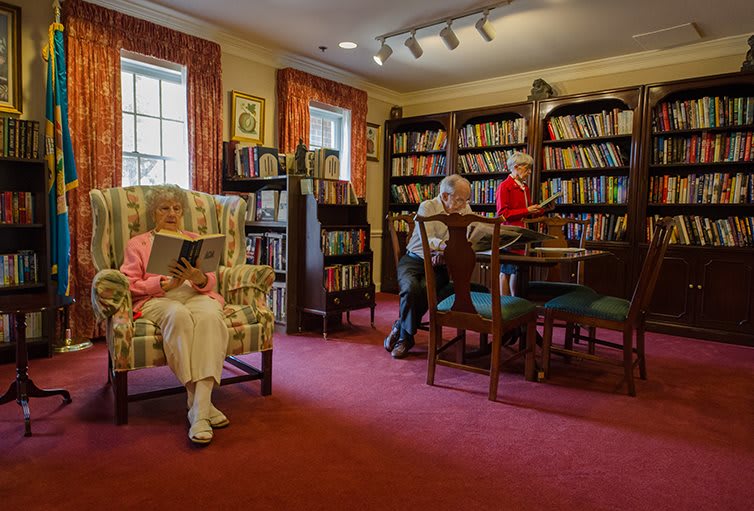 Elderly individuals enjoying a quiet reading session in a cozy library.