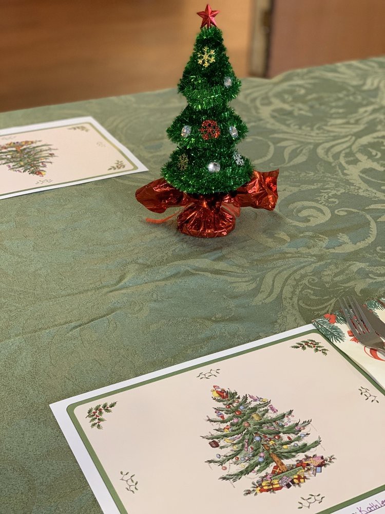 A festive Christmas-themed table setting with a decorative tree and place cards.