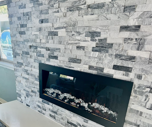 A sleek modern fireplace framed by a stylish stone wall, adding elegance to the living space.