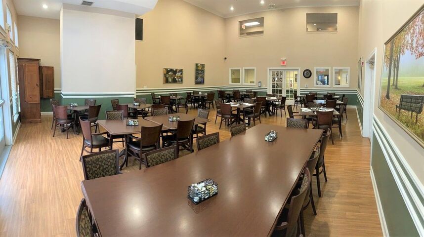 An empty dining hall with neatly arranged tables and chairs, ready for an event.