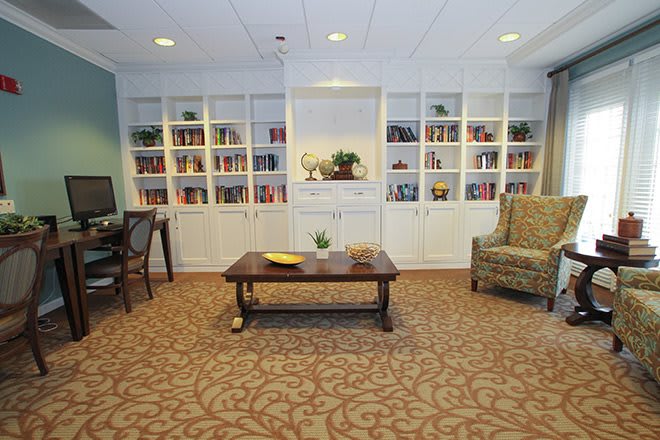 A cozy library space featuring built-in bookshelves, a central coffee table, and comfortable seating.