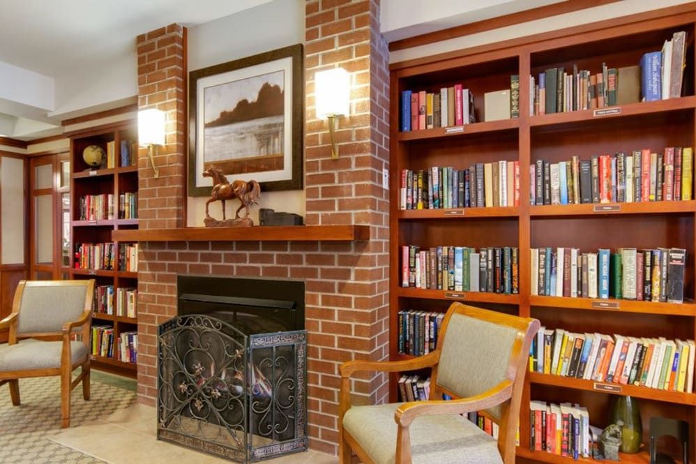 A cozy reading nook with a brick fireplace and a well-stocked bookshelf.