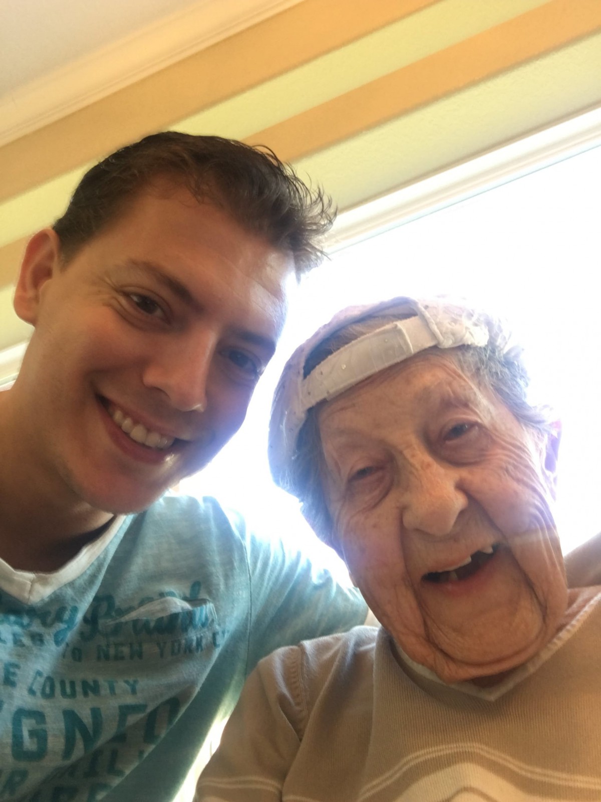 A cheerful selfie with an elderly person wearing a cap.