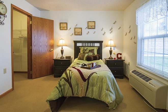A cozy bedroom with a single bed, wall art, and warm lighting from bedside lamps.