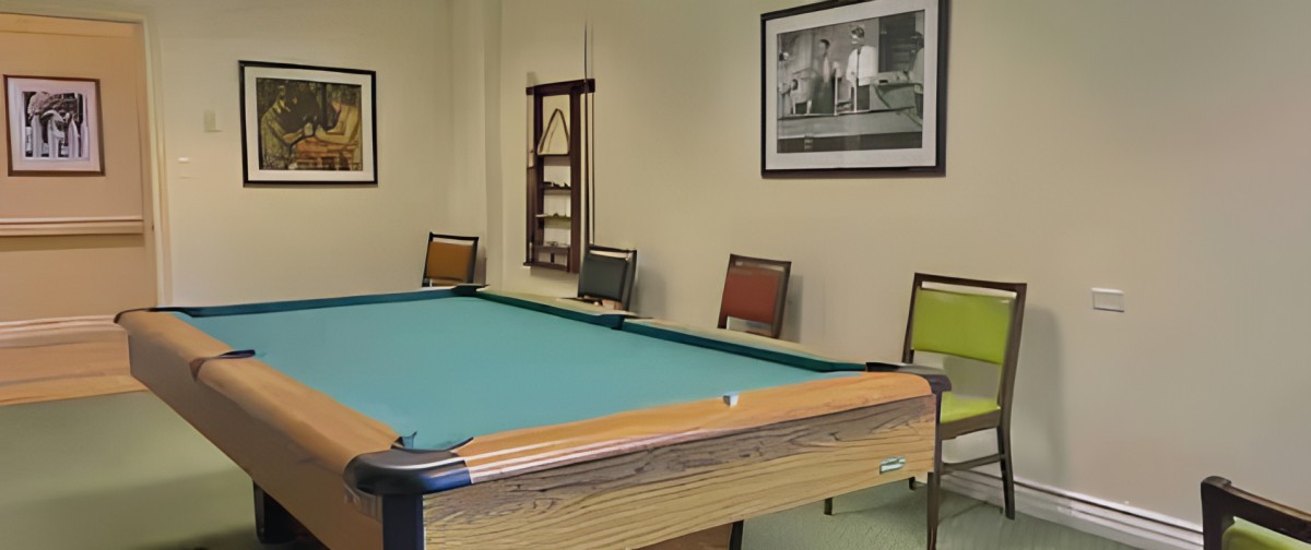 A room with a billiards table and chairs along the wall.