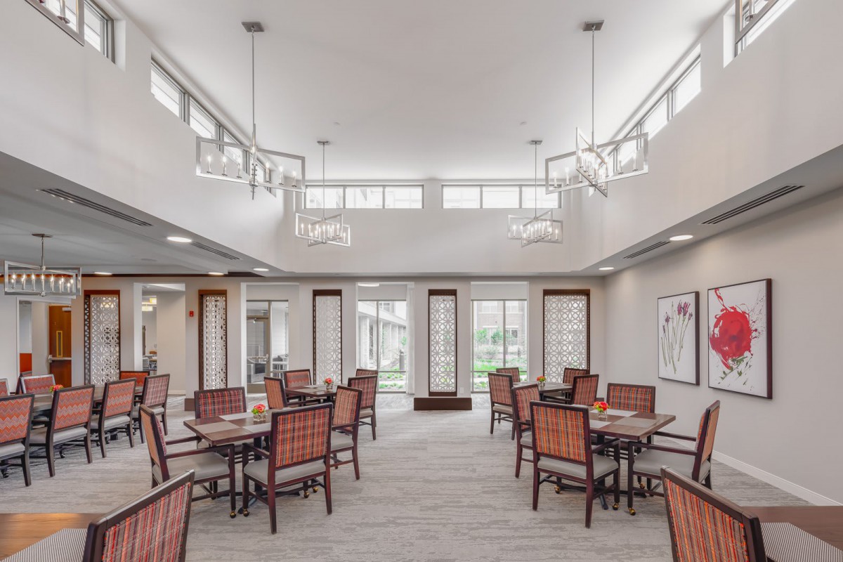 A modern and spacious dining area with neatly arranged tables and chairs, featuring stylish lighting.