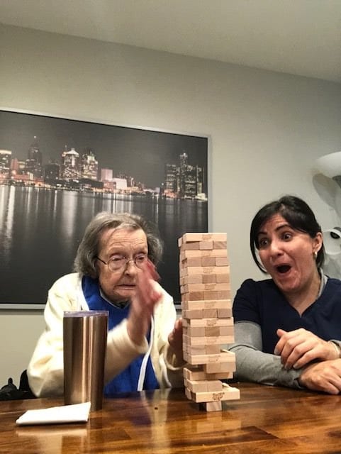 Two women enthusiastically playing a game of Jenga indoors.