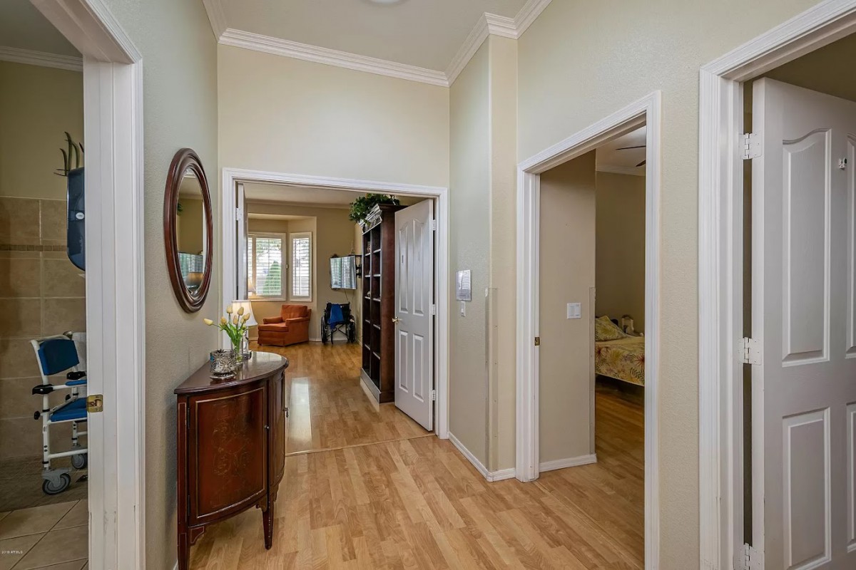 A well-lit hallway with wood flooring and elegant decor, featuring multiple doorways.