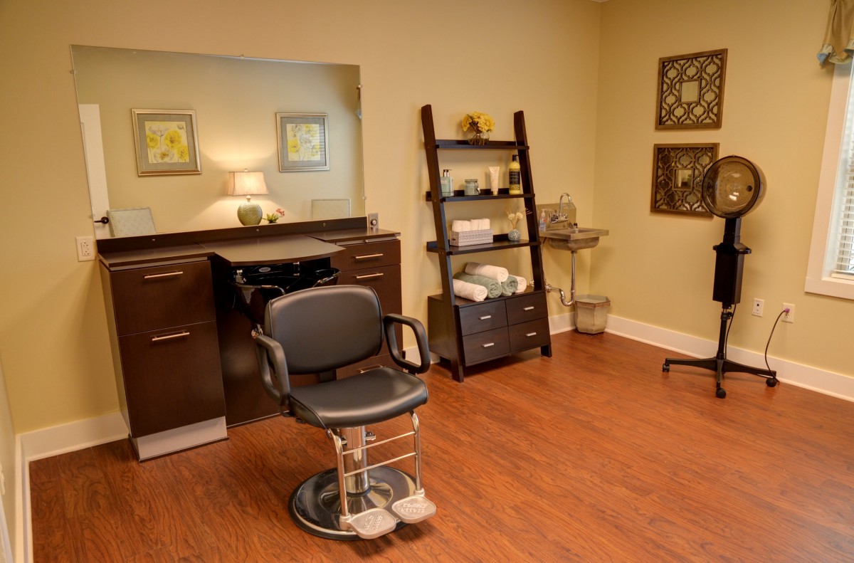 A tidy and well-organized hair salon interior with a barber chair, mirror, and shelves.