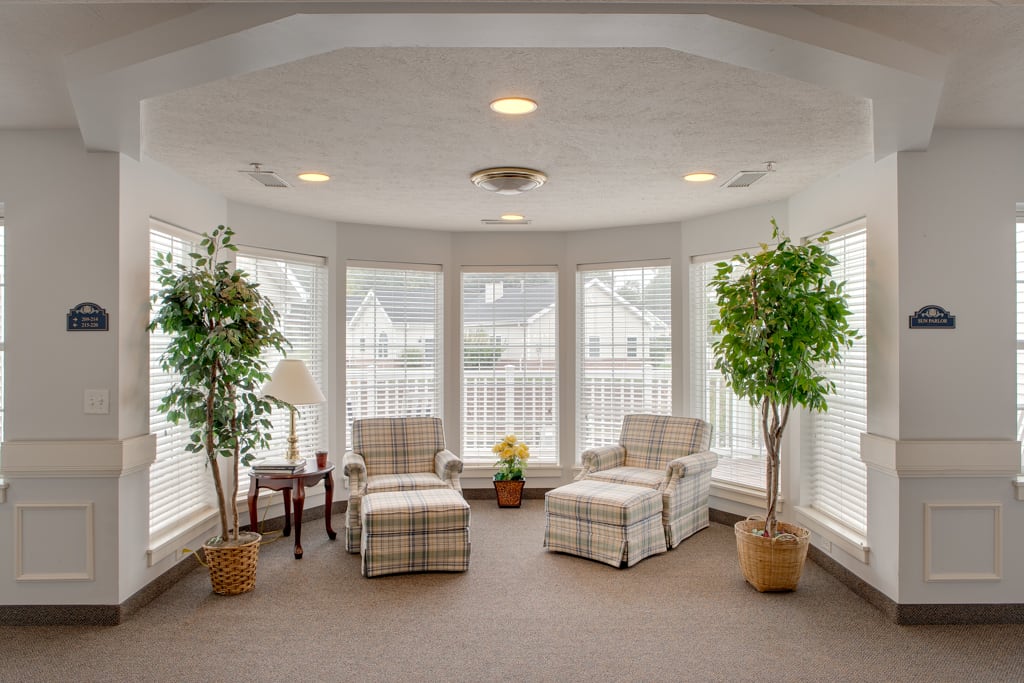 A cozy sunroom with two armchairs, large windows, and indoor plants.