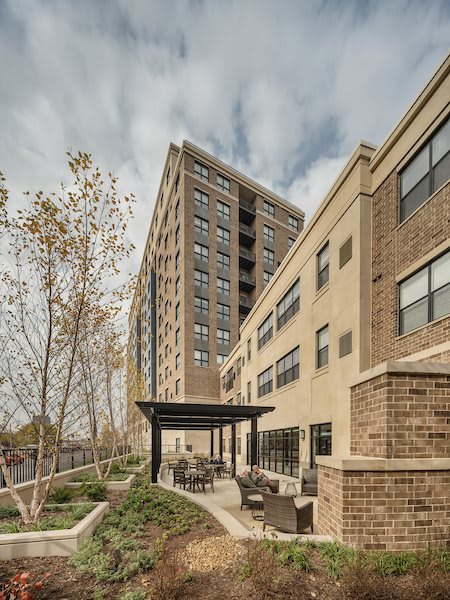 A view of a modern apartment building with an outdoor seating area and overcast sky.
