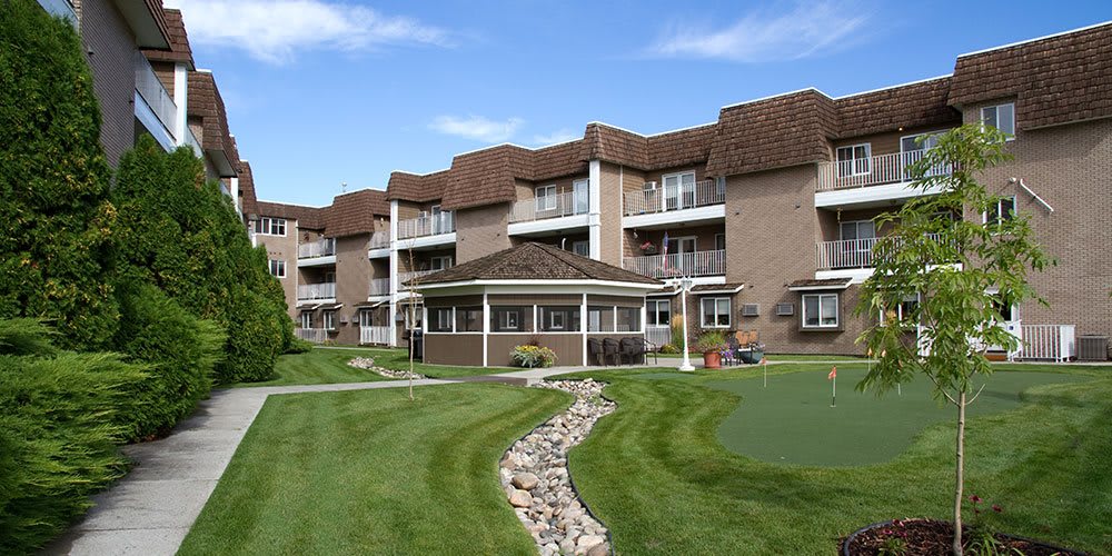A well-maintained apartment complex with lush landscaping and a central gazebo.