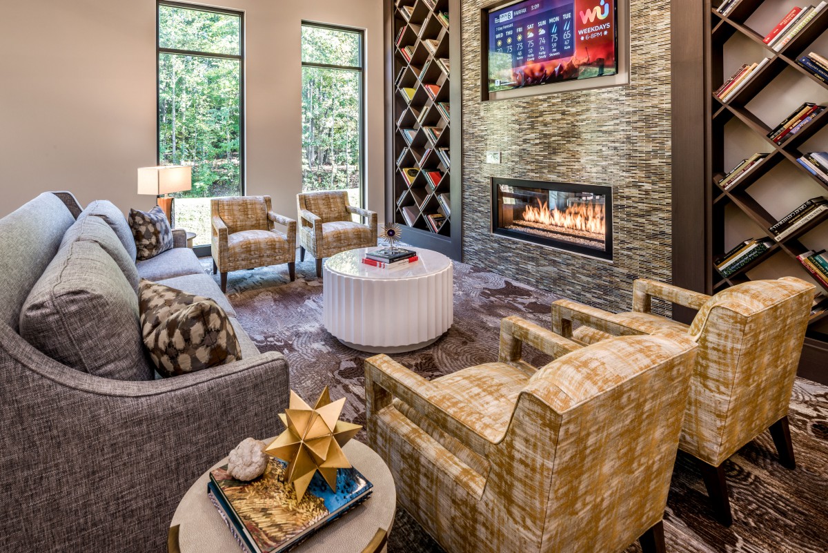A contemporary living room featuring a cozy seating area with a fireplace and a wall-mounted television, enhanced by modern decor and large windows.