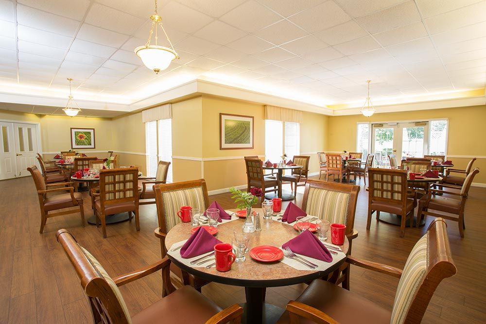 A warmly-lit dining room with round tables elegantly set for a meal.