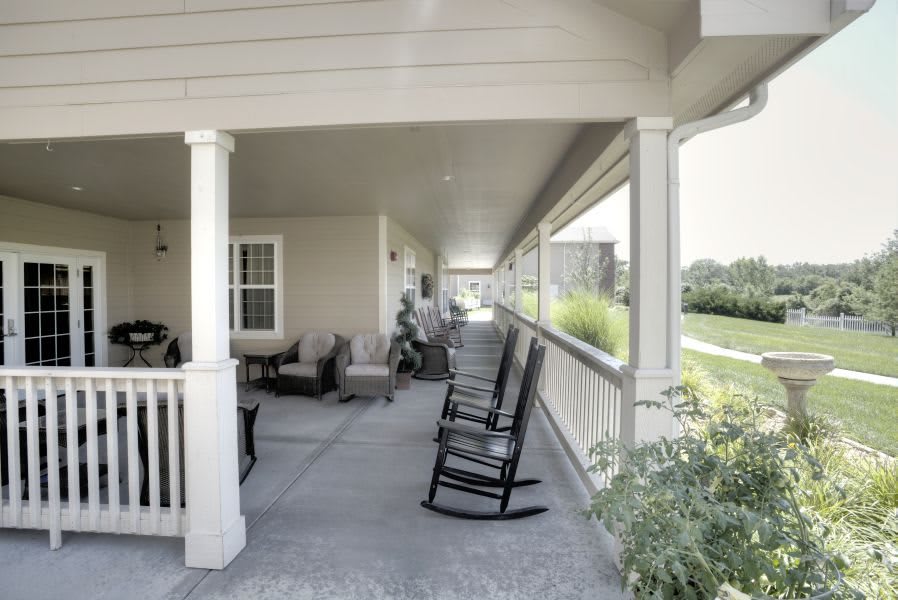 A spacious covered porch with rocking chairs and outdoor seating, offering a relaxing view.