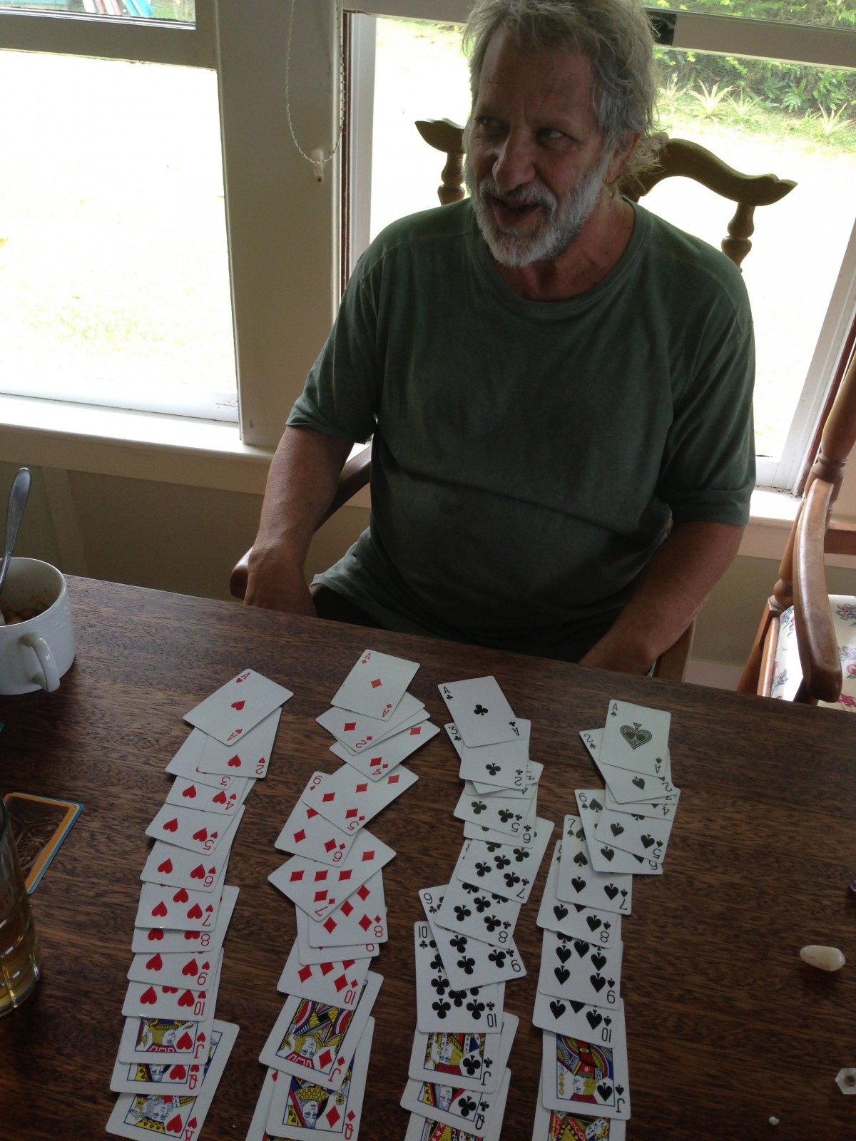 A person sitting at a table with playing cards arranged in columns.