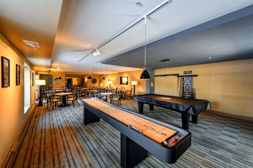 A spacious game room featuring shuffleboard tables and a cozy dining area.