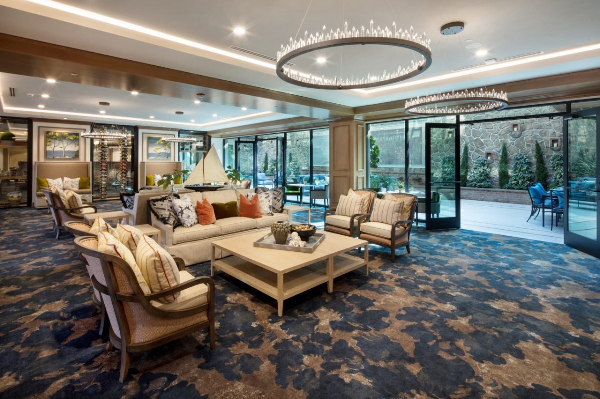 A modern living room featuring comfortable sofas, a stylish chandelier, and glass doors leading to an outdoor area.