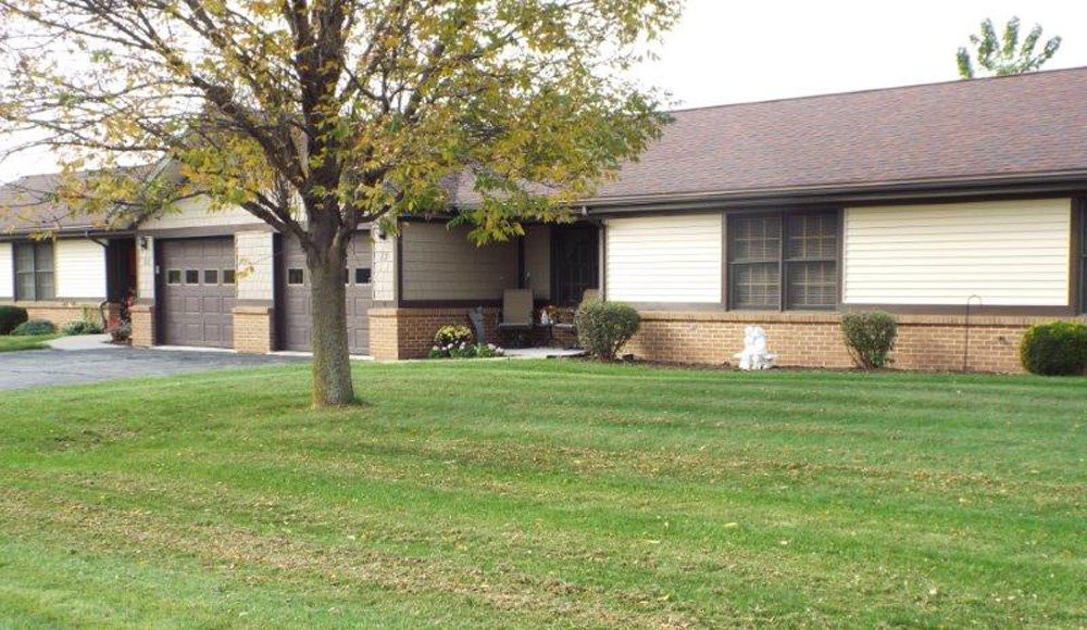A suburban house with a well-kept lawn and a tree in the front yard.