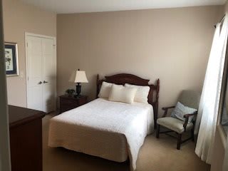 A cozy bedroom with a bed, nightstand, and chair.