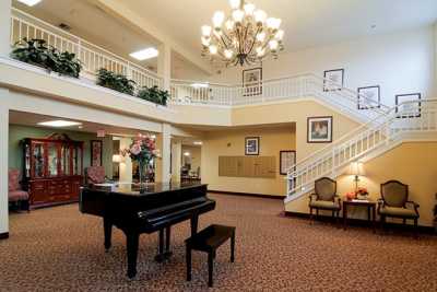 A spacious lobby with a grand piano, elegant chandelier, and a staircase.