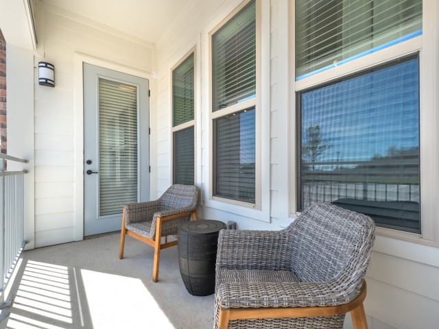 A cozy patio with wicker chairs and a small table, bathed in sunlight.
