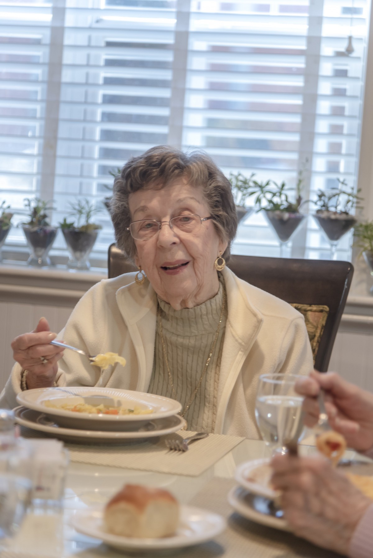 An elderly woman enjoying a meal at the dining table.