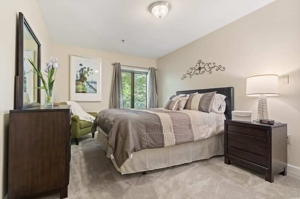 A cozy and well-decorated bedroom featuring a comfortable bed, elegant furniture, and artwork on the walls.