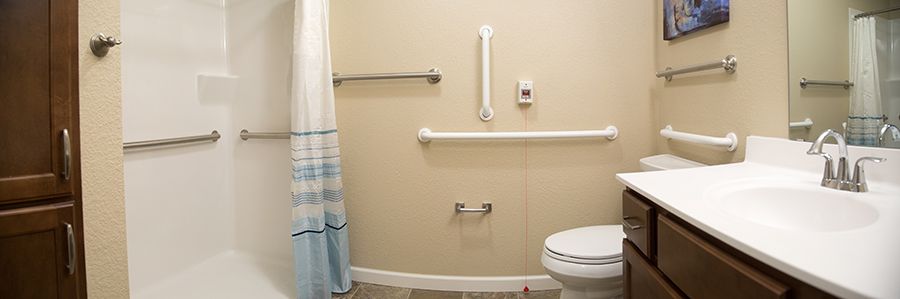 An accessible bathroom equipped with grab bars and a shower curtain.
