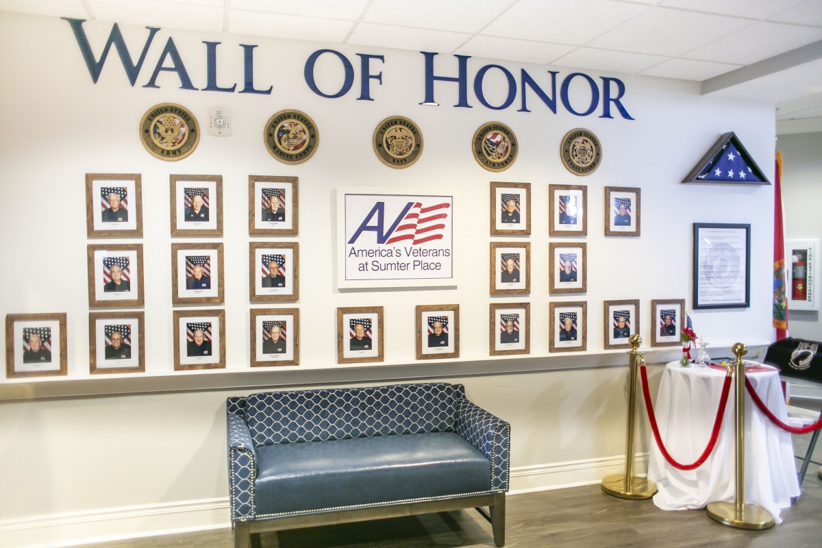 A Wall of Honor display featuring photographs and plaques dedicated to veterans, with a bench placed in front.