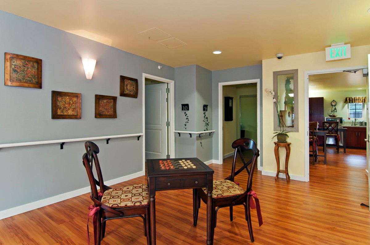 A cozy room with a small table and two chairs, featuring wooden flooring and elegant wall decorations.