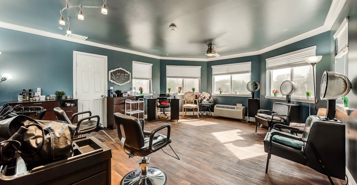 A modern salon interior featuring stylish chairs, large mirrors, and ample natural light.