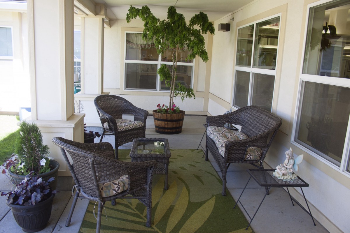 A cozy patio area featuring wicker furniture and a large potted plant.