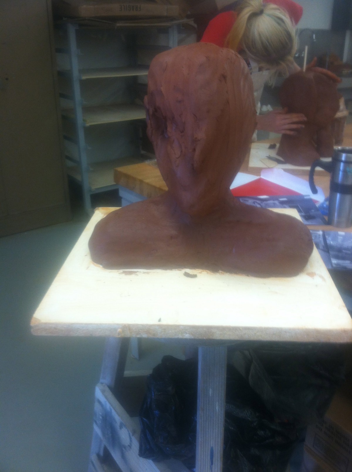 An unfinished clay sculpture of a bust in an art studio.