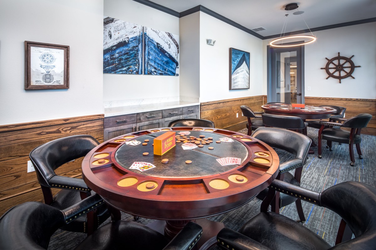 A well-appointed game room featuring a poker table surrounded by chairs, adorned with artwork on the walls.
