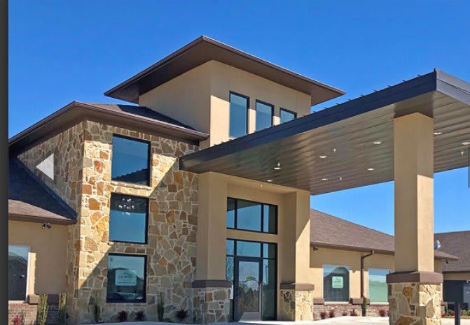 A modern building with a stone facade and large windows under a clear blue sky.