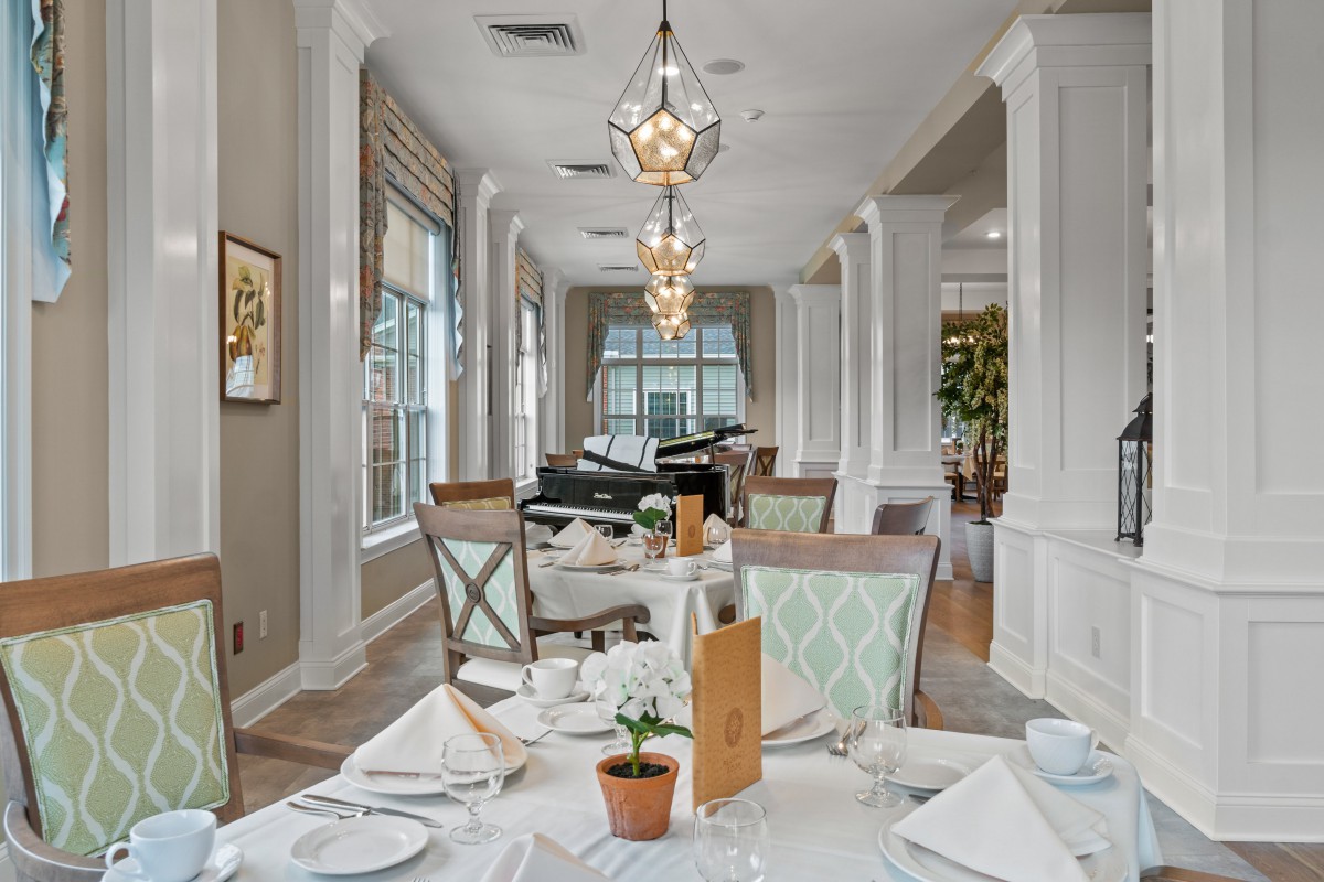 An elegant restaurant dining room with neatly set tables and stylish chandeliers.