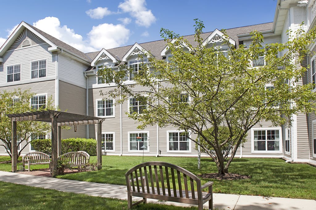 A serene garden area with a bench and pathway in front of a residential building.