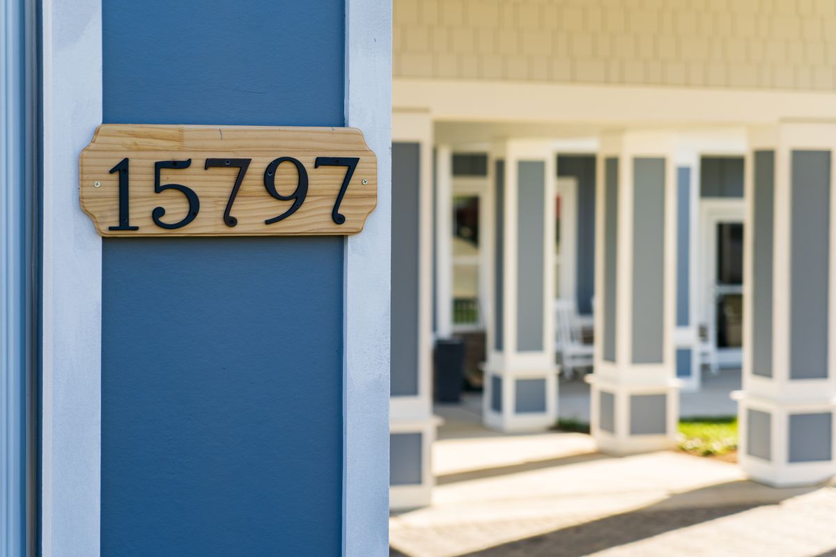 A house with the visible address number 5797 displayed on a wooden plaque, showcasing part of the home's exterior and porch area.