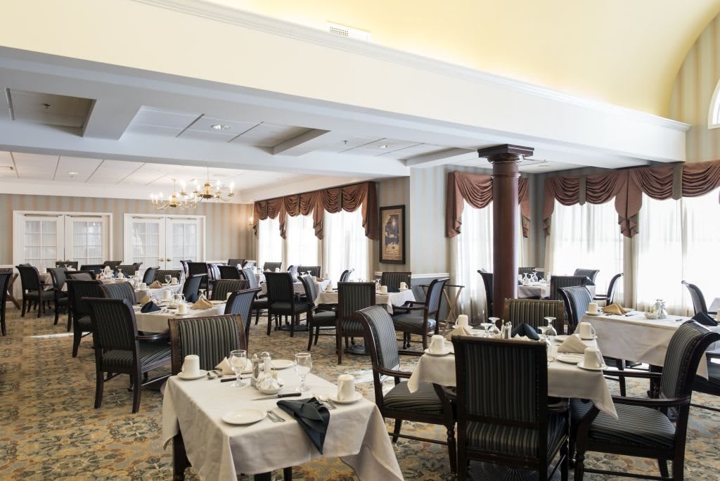 An elegant restaurant dining room featuring neatly arranged tables and chairs with formal place settings.