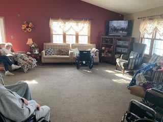 A cozy living room with sofas, a television, and wheelchairs.