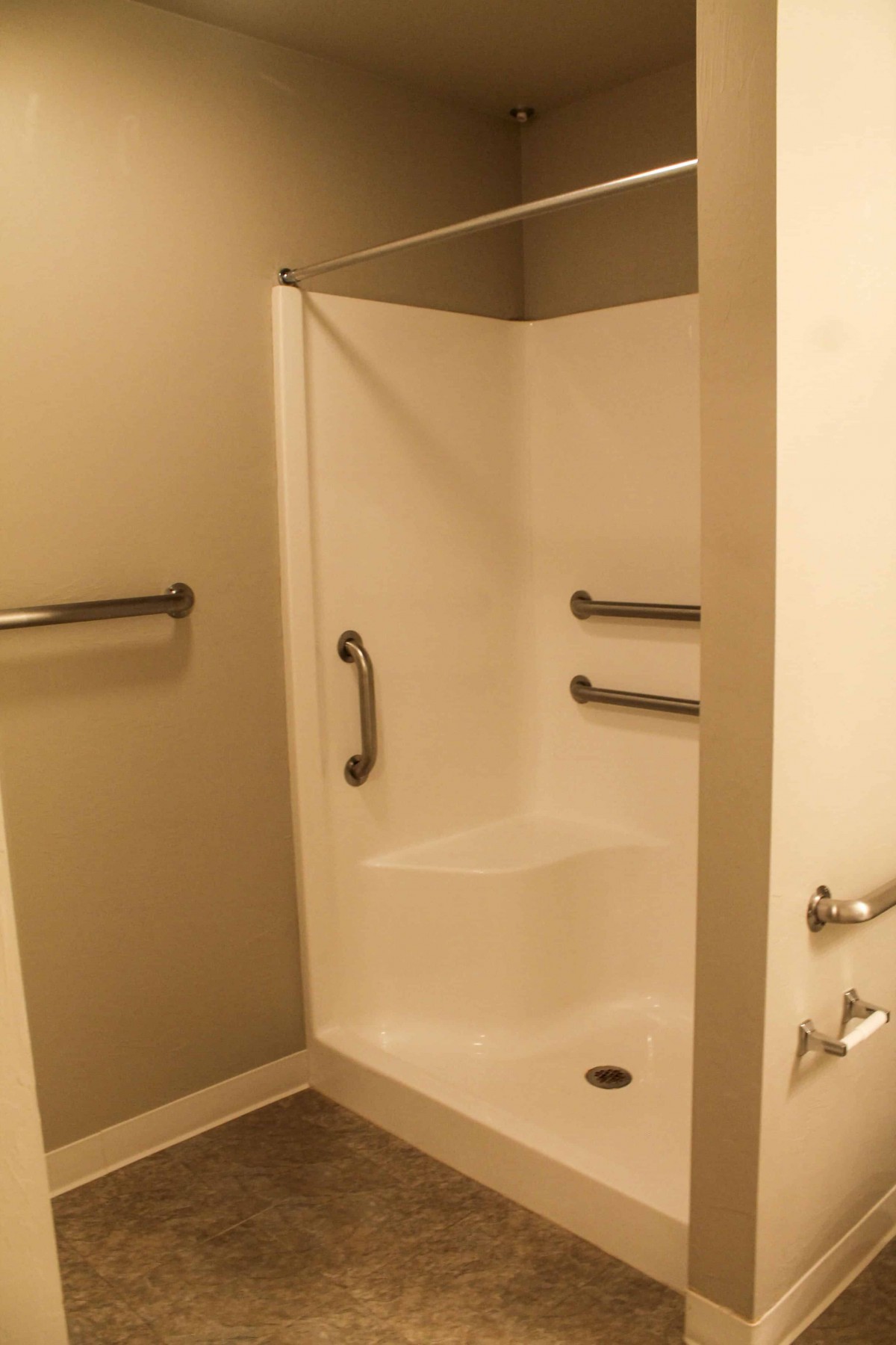 A modern, accessible shower with grab bars in a clean bathroom.