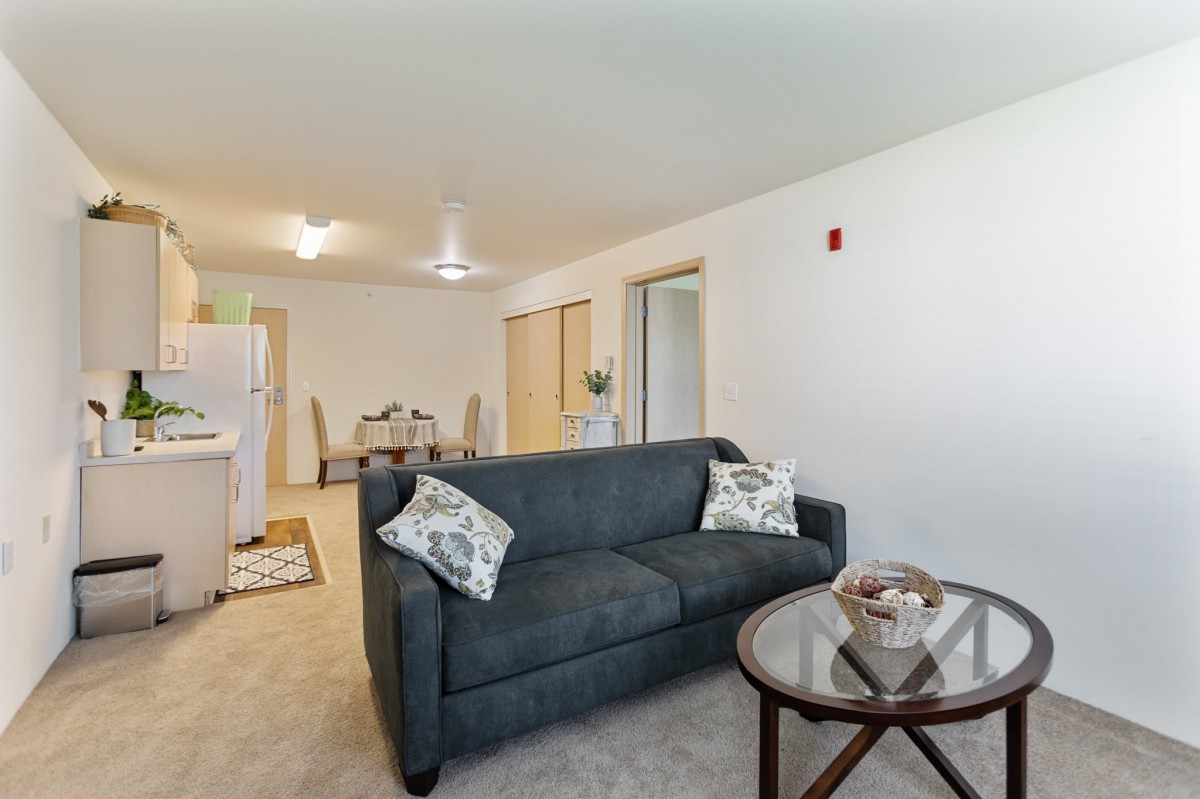 A cozy living room with a sofa, coffee table, and dining area in an apartment.