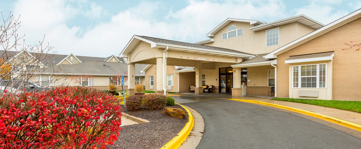 A building entrance with a covered driveway and landscaped surroundings.