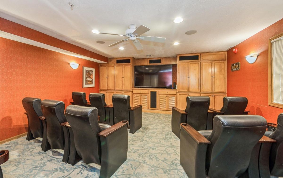 A cozy home theater with comfortable seating and a large screen, surrounded by wooden cabinetry.