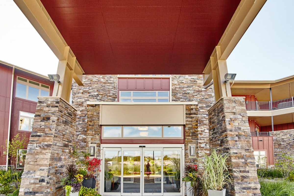 A modern building entrance with a stone facade and decorative plants.