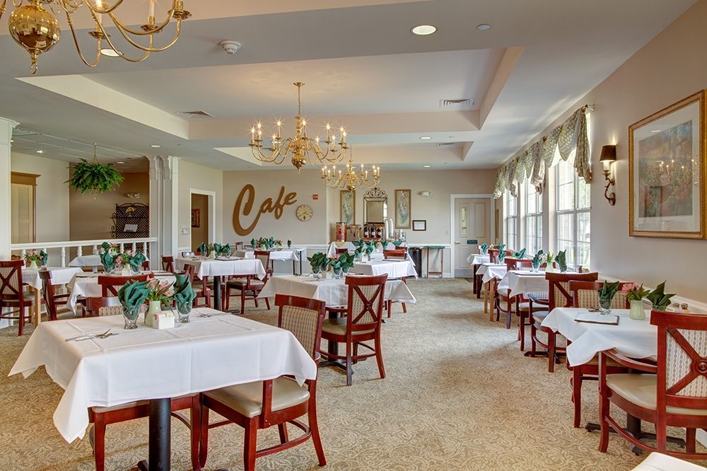 An elegant restaurant dining area with neatly arranged tables and chairs, adorned with chandeliers and large windows.