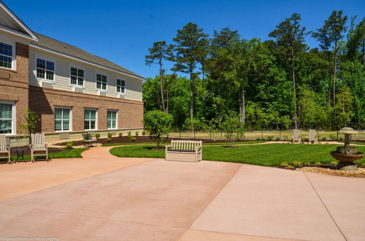 A modern building with a landscaped garden and pathway under a clear blue sky.